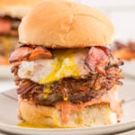 A large burger with bacon and eggs on it.