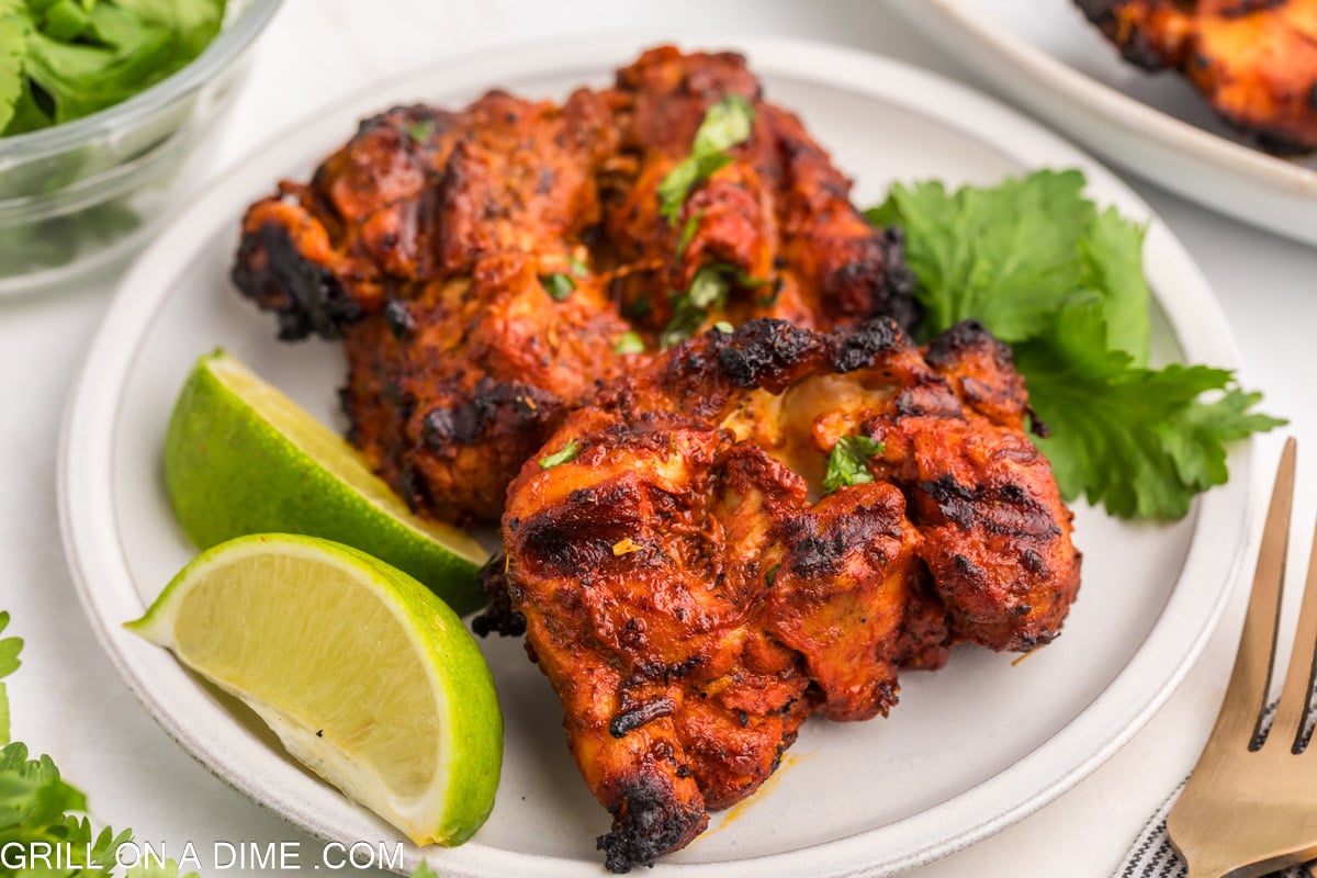 Pollo Asada chicken stacked on a plate with a side of lime wedges.