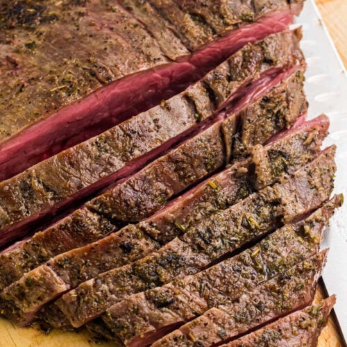 Sliced medium-rare flank steak Blackstone on a cutting board, showing a pink center and a seasoned, browned crust.