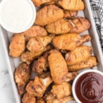 crispy baked chicken wings with dipping sauces on a metal tray