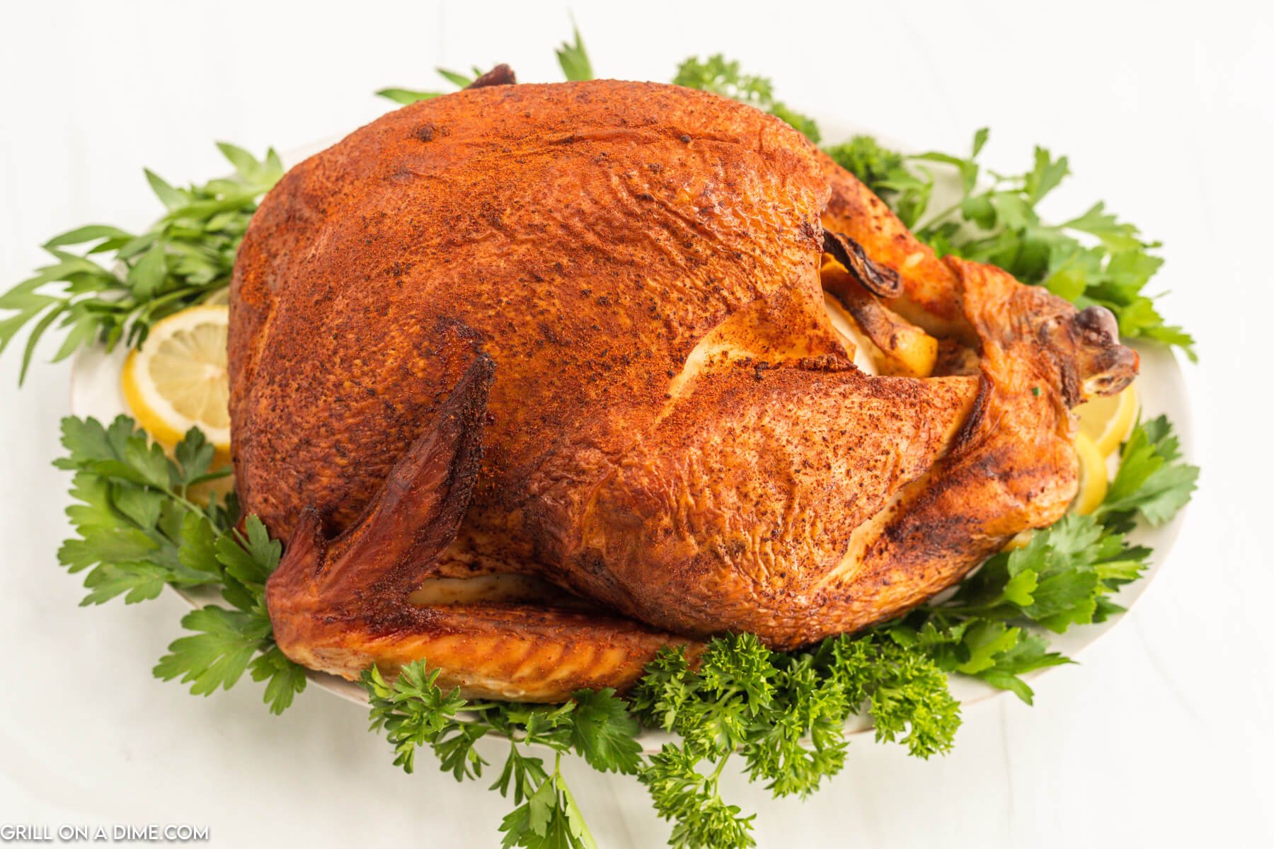 Smoked Turkey on a platter with fresh greens and slice lemons