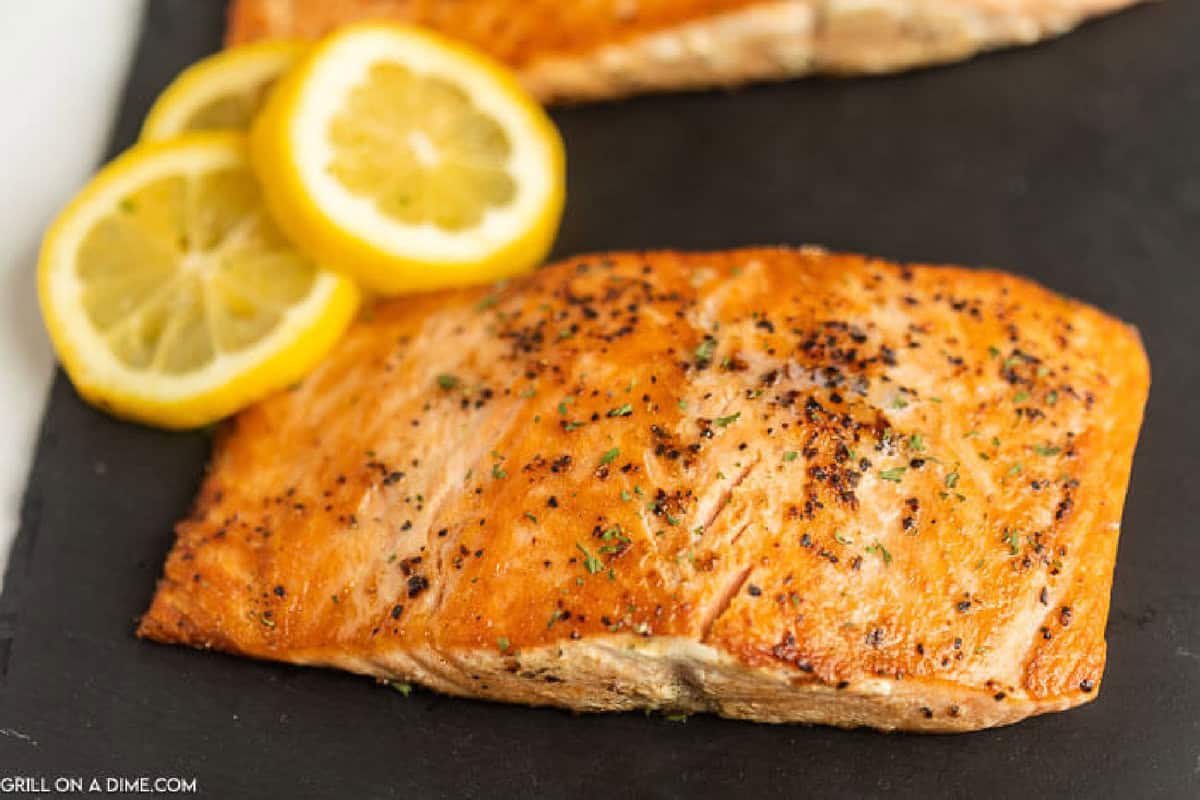 Blackstone Salmon on a black slate platter with a side of slice lemon wedges