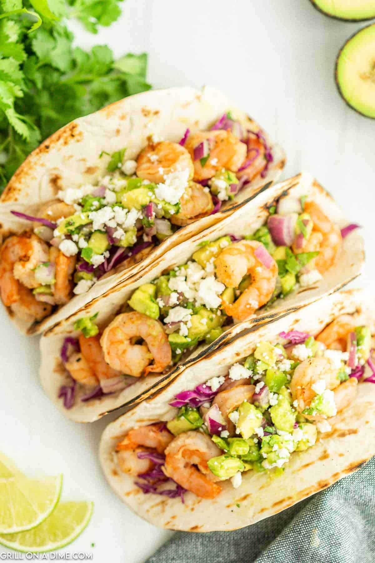 Close up image of shrimp tacos topped with diced avocado. 