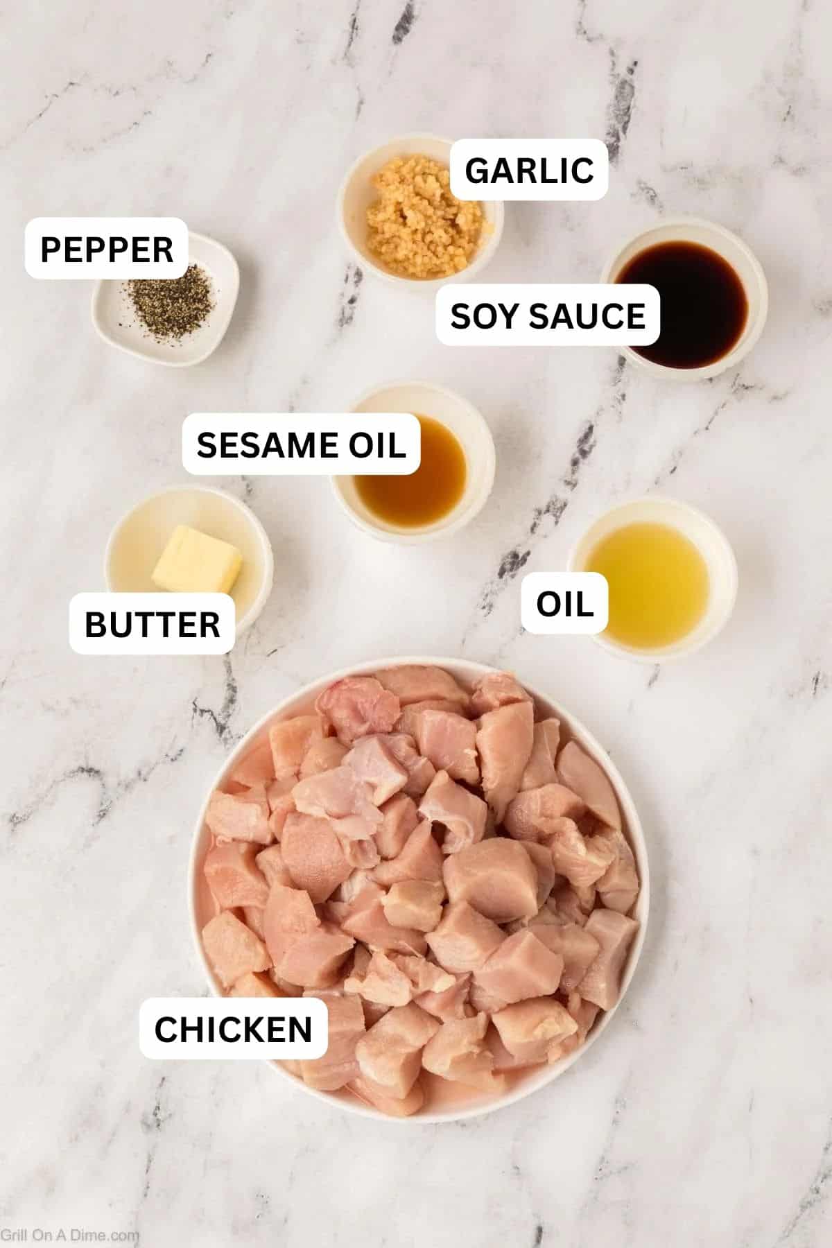 Ingredients needed to make this recipe which include diced chicken, minced garlic, black pepper, soy sauce, butter, honey, and apple cider vinegar, all neatly arranged on a white marble surface.