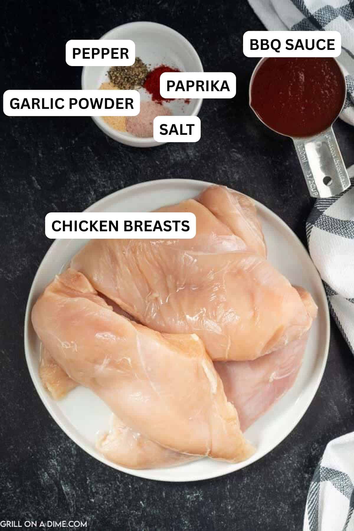 Ingredients need to make this recipe which includes chicken breast on a plate with a measuring cup of BBQ Sauce and a bowl of spices.
