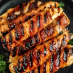Bacon wrapped chicken tenders stacked on a plate.