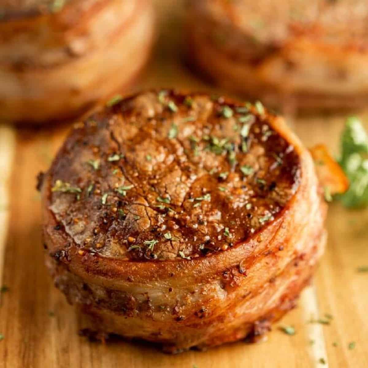 Grilled Filet wrapped in bacon on a wooden surface.