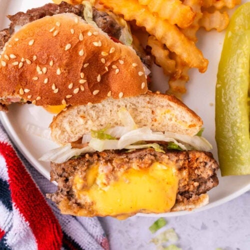 Juicy cheeseburger with melted cheese, topped with fresh lettuce and served with crispy fries and pickles.