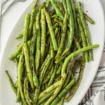 Grilled green beans on a white plate.
