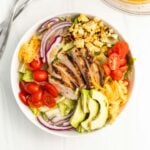 Grilled Chicken salad topped with cherry tomatoes, avocados, cheese, and cheese.