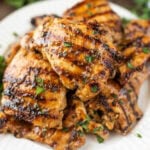 Grilled chicken thighs on a white plate.