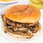 A hamburger with onions and cheese on a white plate.