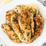 Cooked Chicken Tenders on a plate with slice lemons