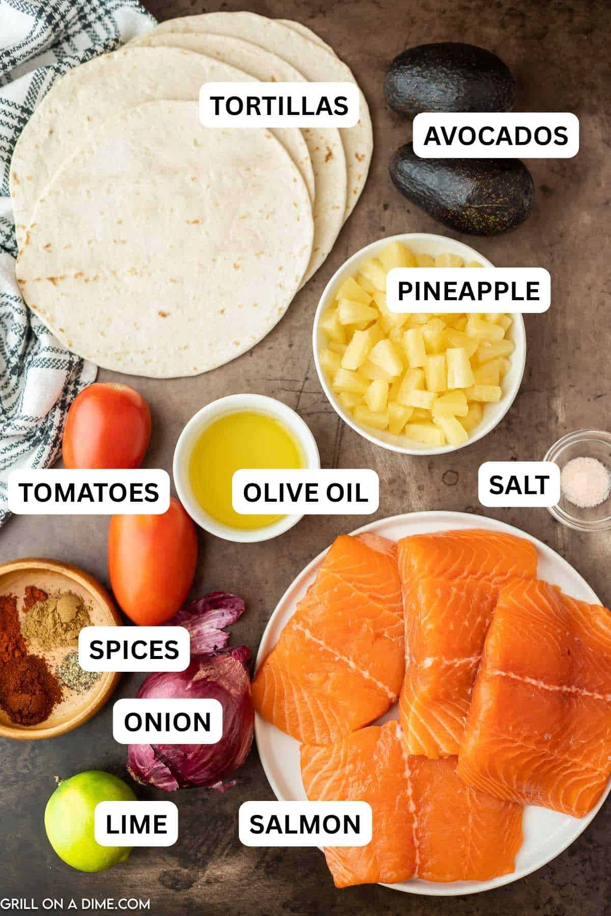 Ingredients needed to make this recipe which includes salmon, olive oil, chili powder, paprika, cumin, salt and pepper, lime juice, pineapple tidbits, roma tomatoes, red onion, avocados, flour tortillas, red cabbage and cojita cheese.