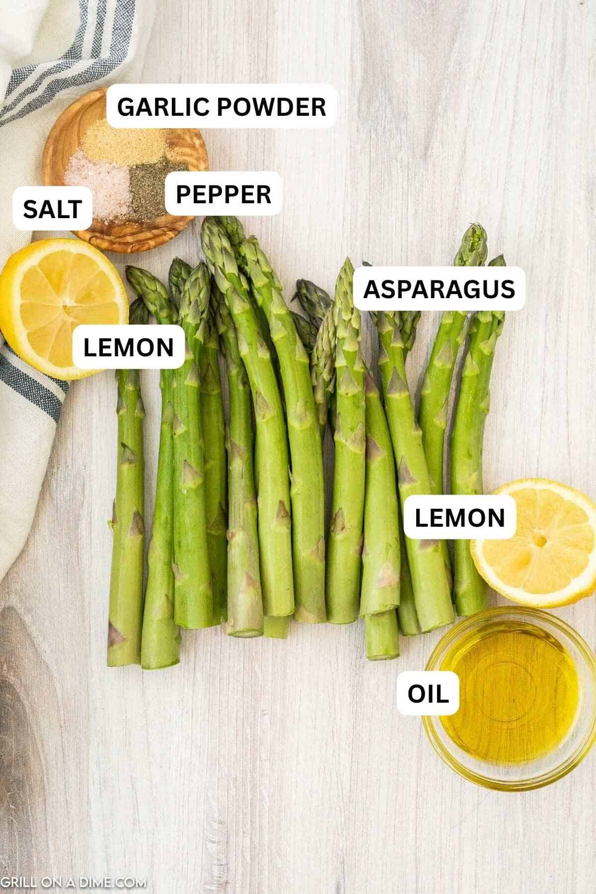 Ingredients needed to make this recipe which includes fresh asparagus, olive oil, kosher salt, black pepper, garlic powder, and lemon.