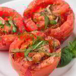Grilled Tomatoes topped with fresh basil on a white plate