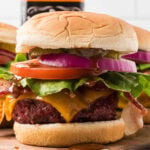 Savory cheeseburger with lettuce, tomato, pickles, onions, and melted cheese on a toasted bun. Perfect for grilling recipes and outdoor cooking.