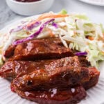 Bbq ribs on a white plate with coleslaw and coleslaw.