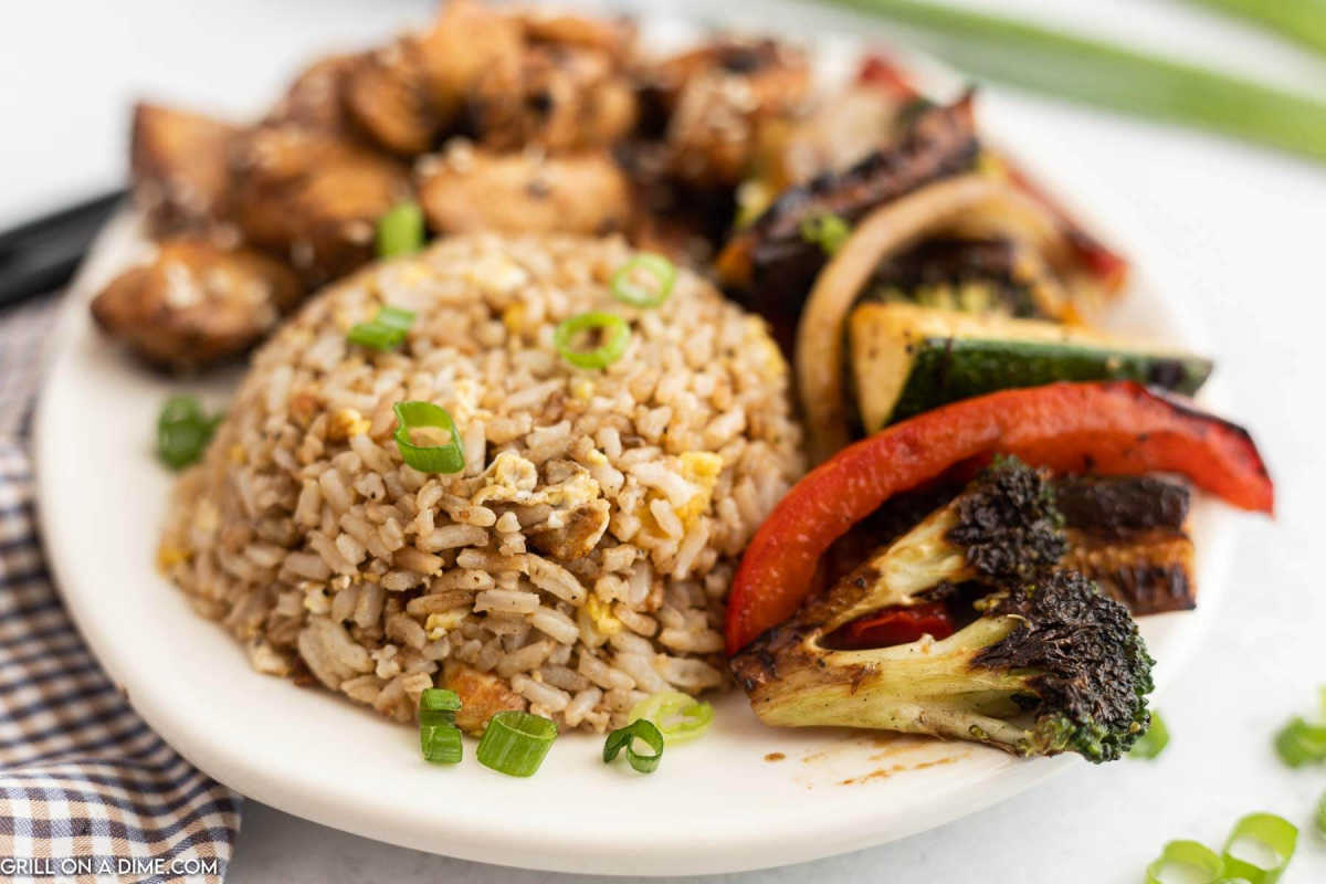 Hibachi Rice on a white plate with hibachi vegetables on the side.