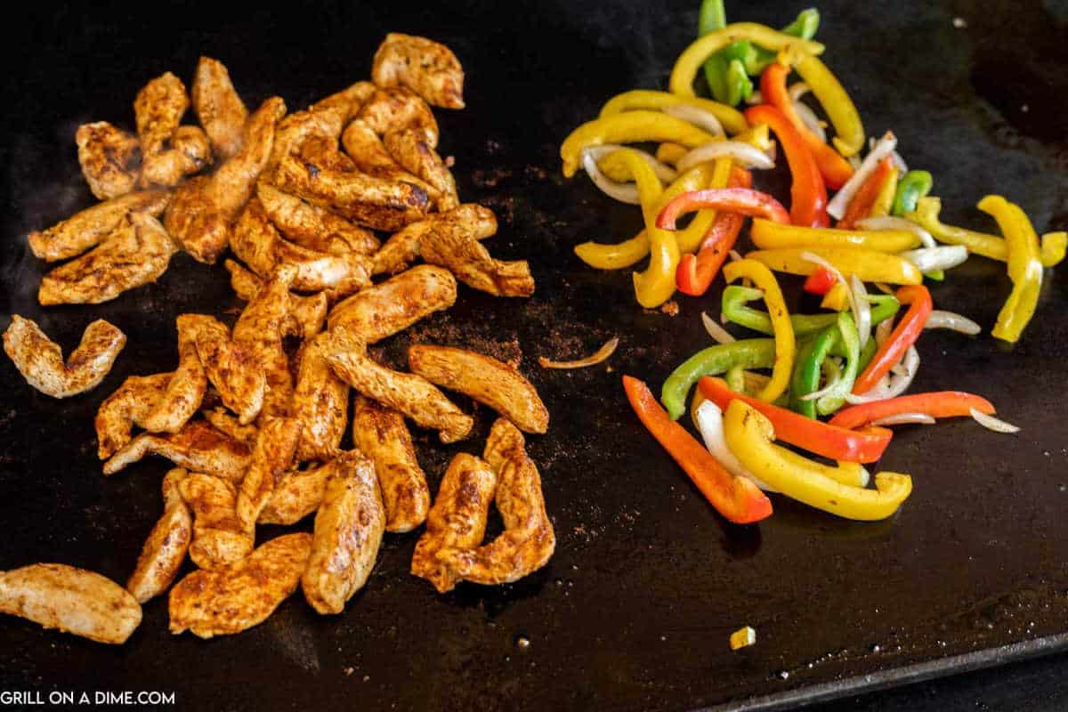 Cooking chicken fajitas on the griddle with a side of bell peppers.