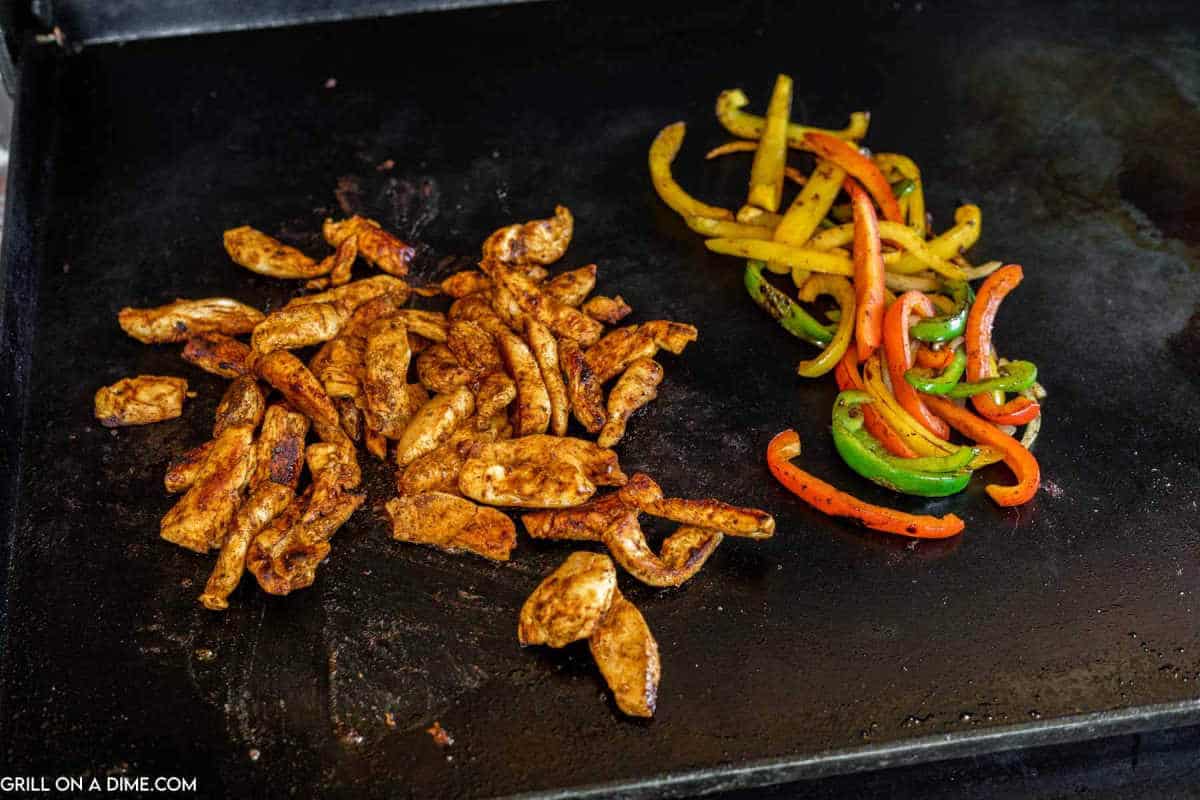 Cooking chicken fajitas on a griddle with bell peppers.