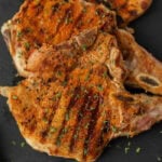 Grilled pork chops on a black slate.