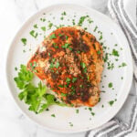 Juicy baked turkey breast with herbs and spices garnished with fresh parsley on white plate