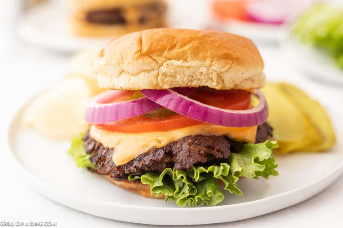 Blackstone cheeseburger topped with lettuce, tomato, and red onions.