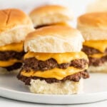 Three cheeseburger sliders on a white plate.