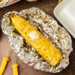 corn on the cob grilled with butter and seasoning in aluminum foil, perfect for summer barbecues and outdoor cooking
