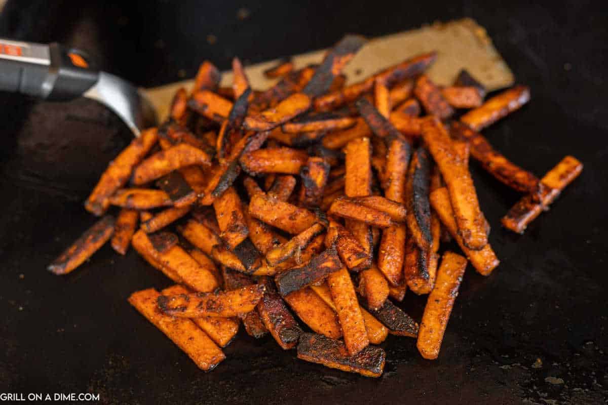 Sweet Potato Fries on the griddle with a spatula.