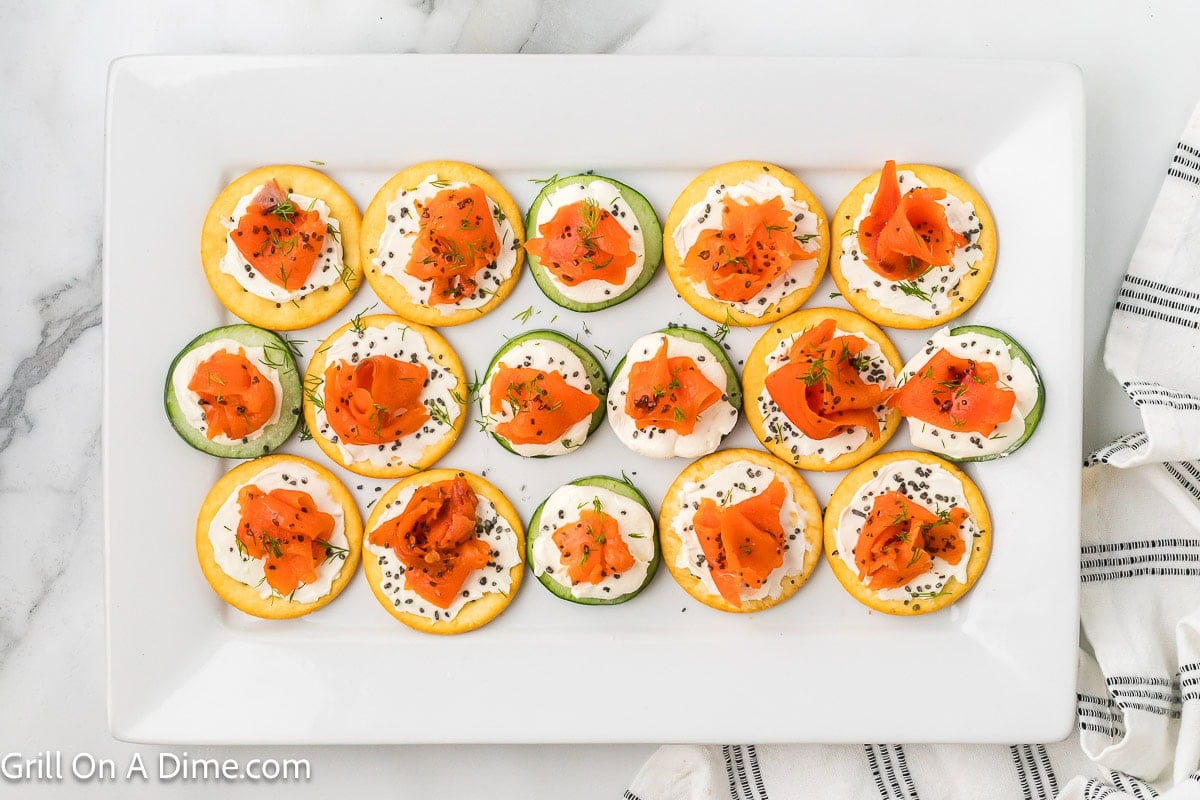 Cold Salmon slices topped on crackers and cucumbers with cream cheese spread