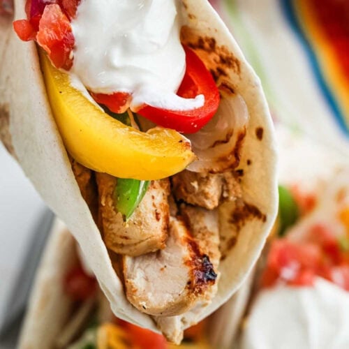 Juicy grilled chicken fajita wrap with colorful peppers, tomatoes, and creamy sauce. Perfect for a delicious Mexican-inspired meal.