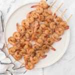 Grilled shrimp skewers on a white plate.