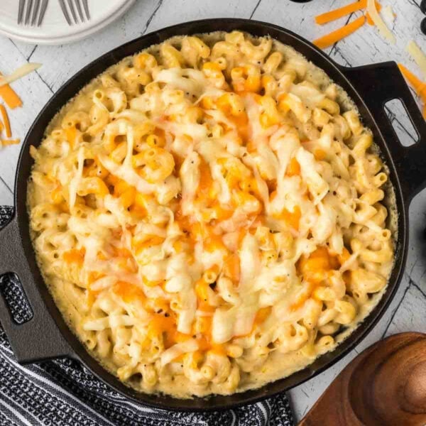 Mac and cheese in a cast iron skillet topped with melted cheese.