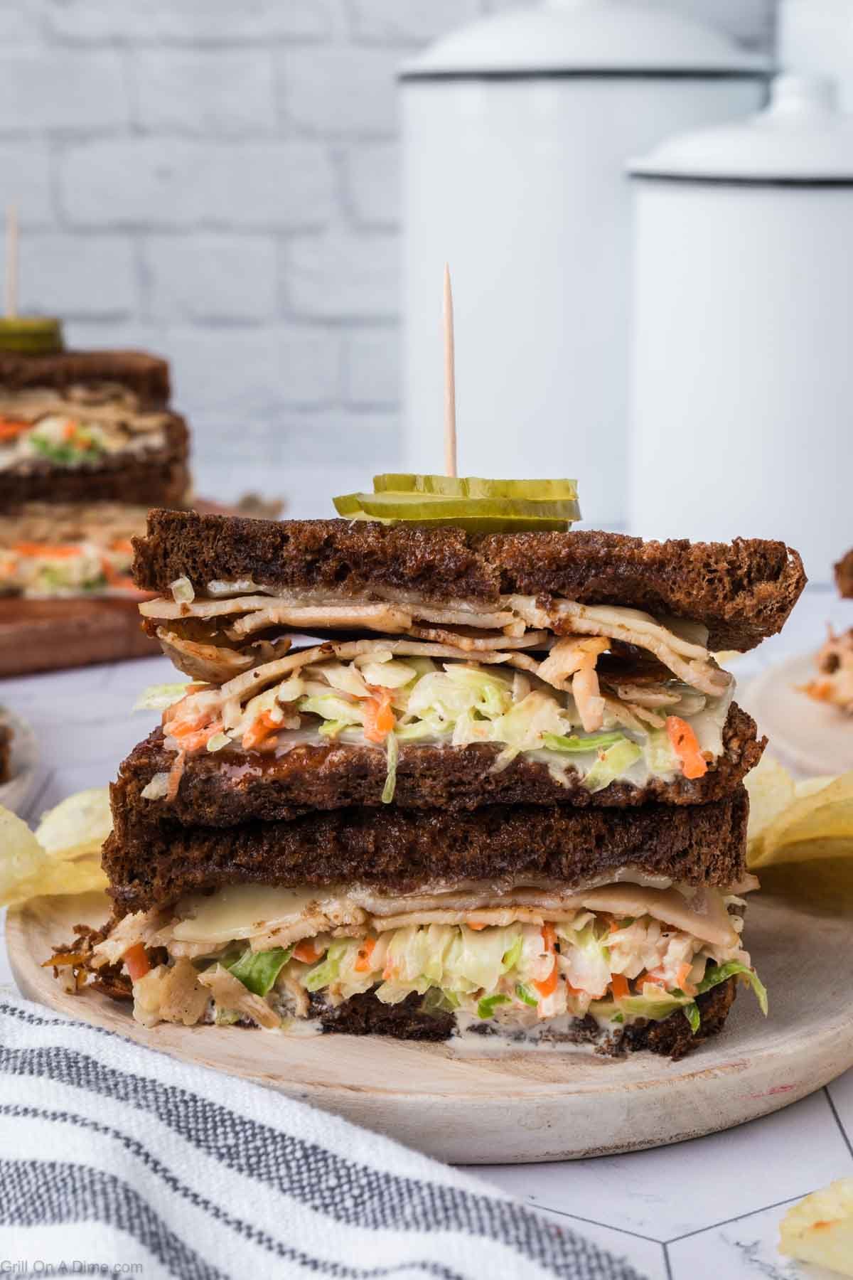 Rachel Sandwich cut in half stacked on a plate showing the layers of deli turkey and coleslaw