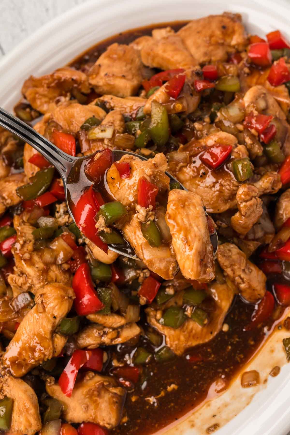 Bourbon Chicken on a platter with a serving on a spoon