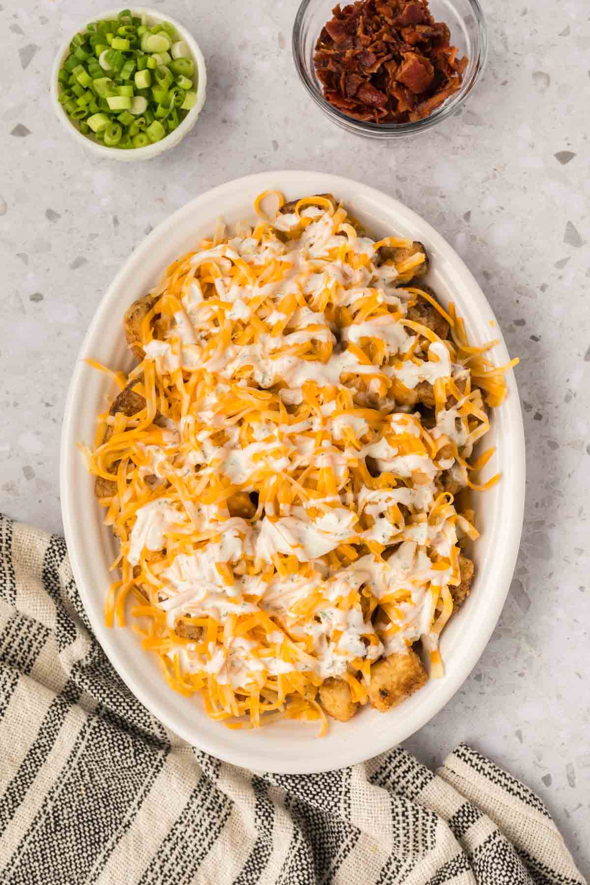 Drizzle of ranch mixture over the top of the shredded cheese and tots