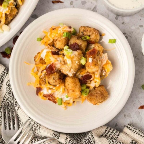 Tator Tot Casserole topped with melted cheese, sour cream and chopped bacon