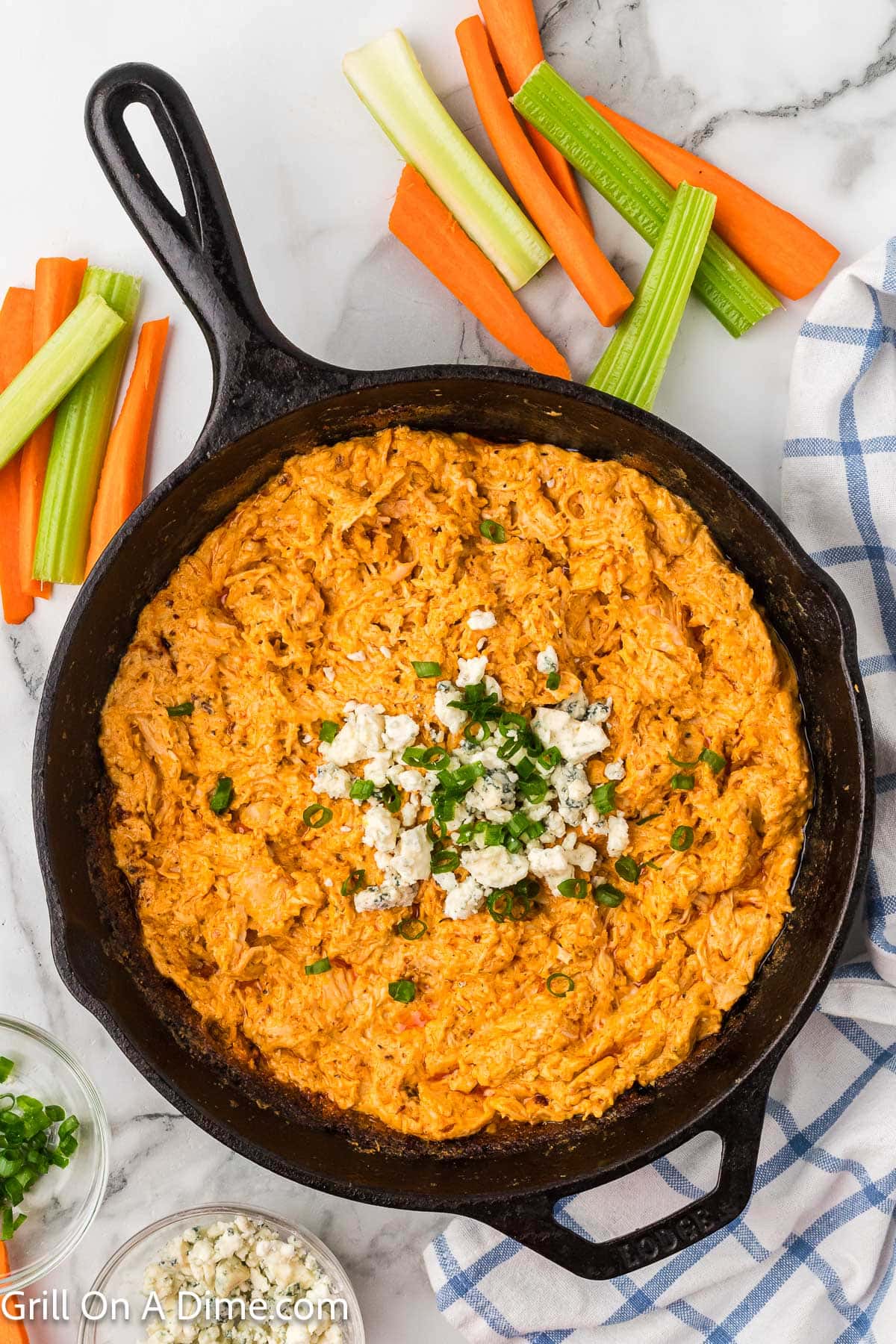 Buffalo Chicken Dip in a cast iron skillet with a side of fresh veggies