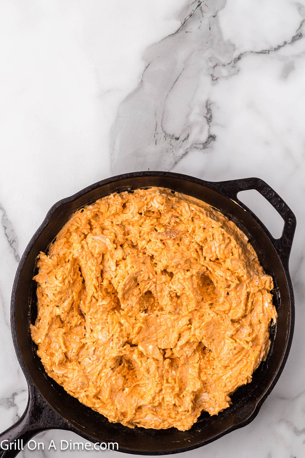 Spreading the buffalo chicken dip into the cast iron skillet dip
