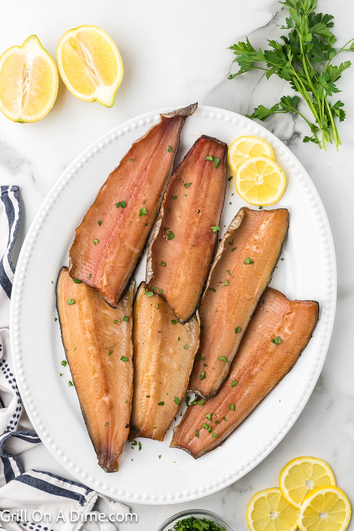 Smoked Trout Fillets on a white serving platter with lemon slices on the side
