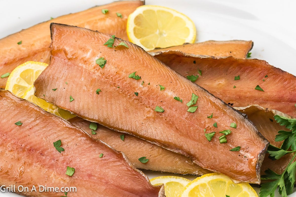 Smoked Trout Filets stacked on a platter with a side of lemon slices 
