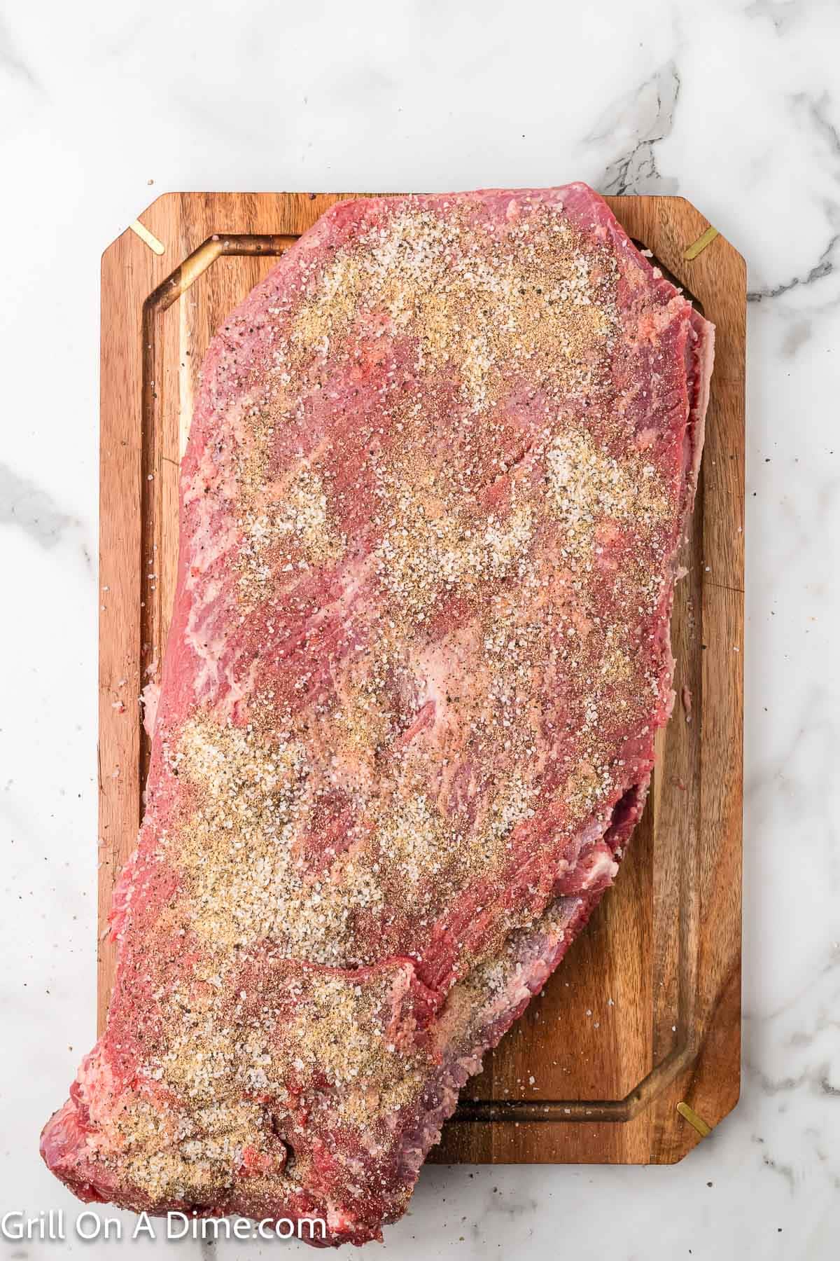Seasoned raw brisket on a cutting board
