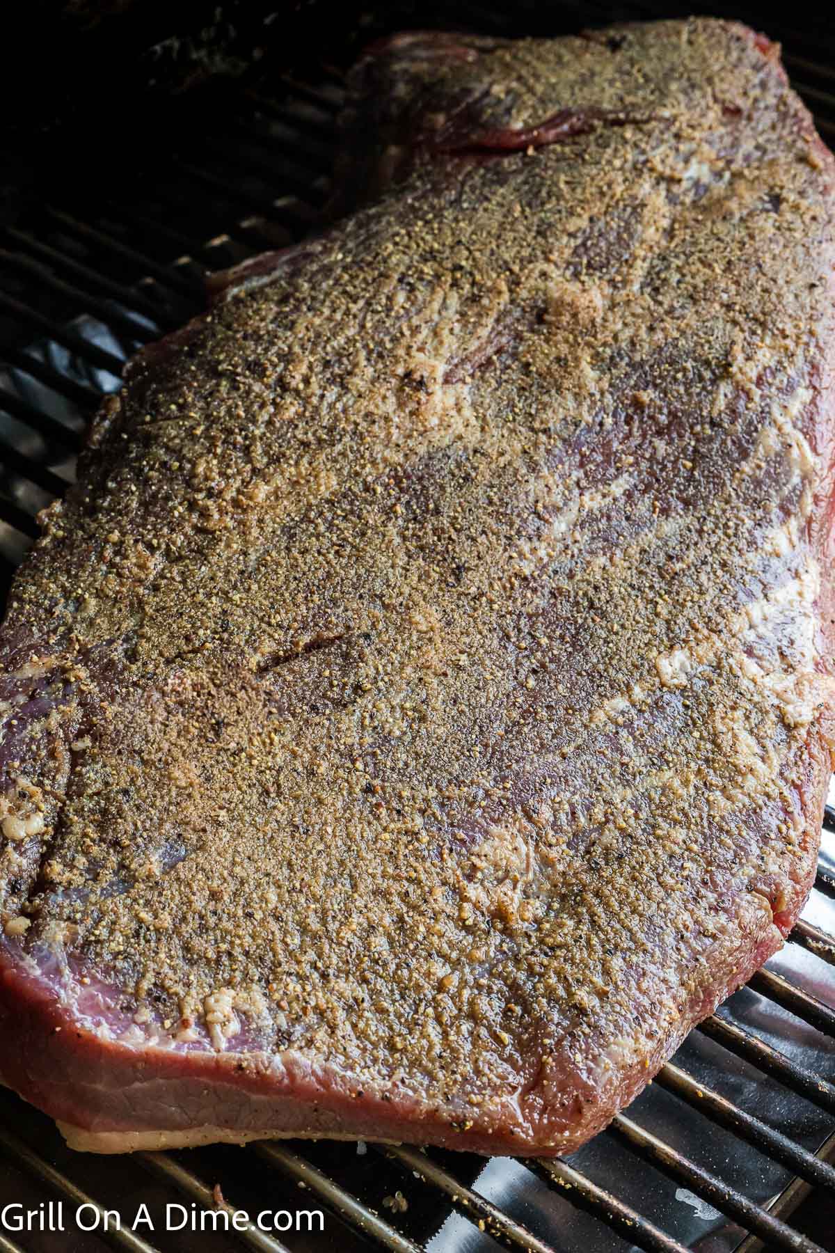 Placing the seasoned brisket on the grill grates