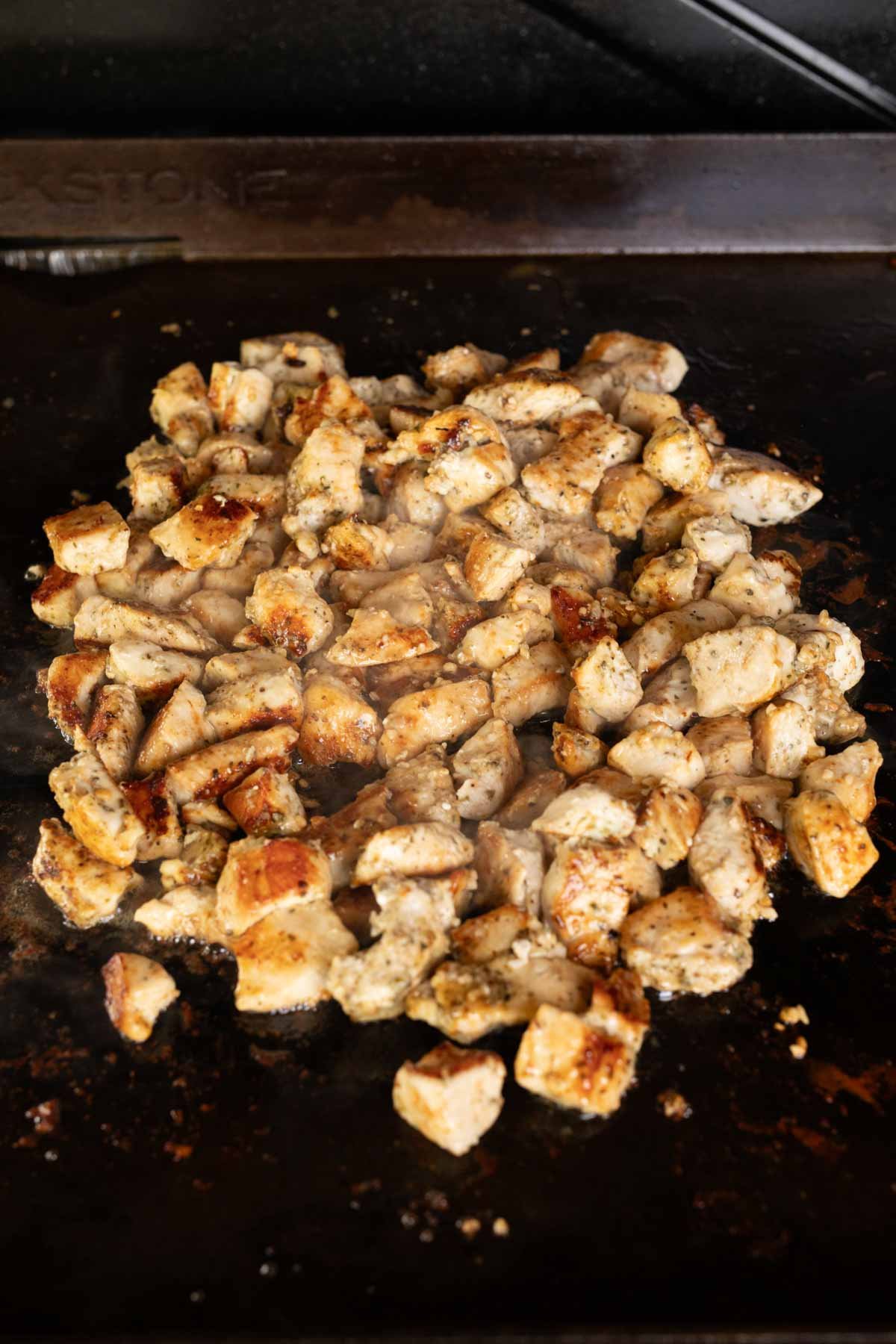 Cooked chicken bites on the Blackstone Griddle tossed with garlic butter
