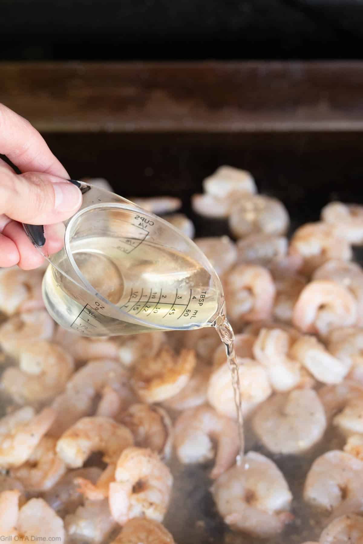 Pouring the wine on the shrimp on the griddle