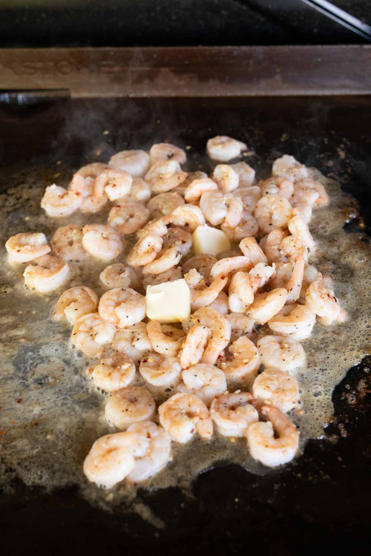 Cooking shrimp on the griddle in the melted butter sauce