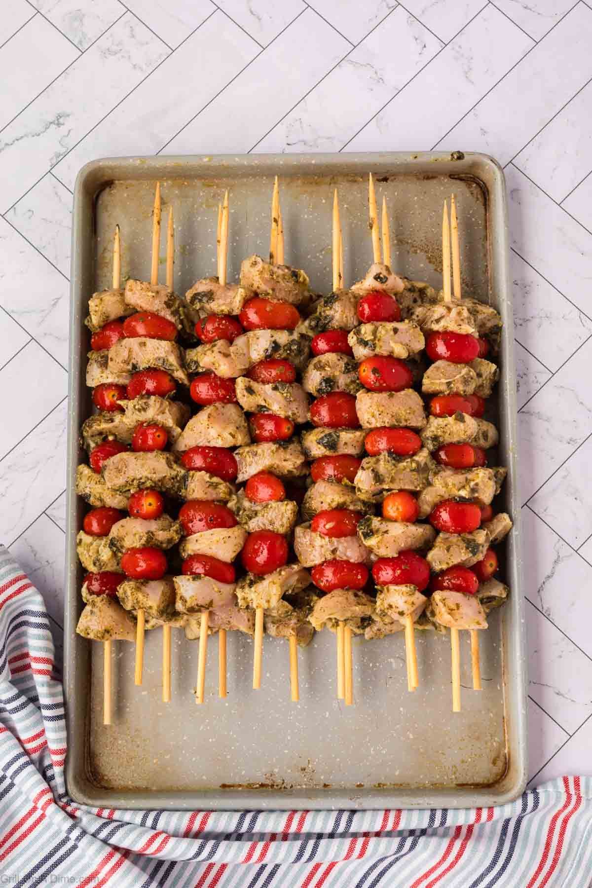 Marinated chicken chunks and cherry tomatoes thread on a wooden skewers