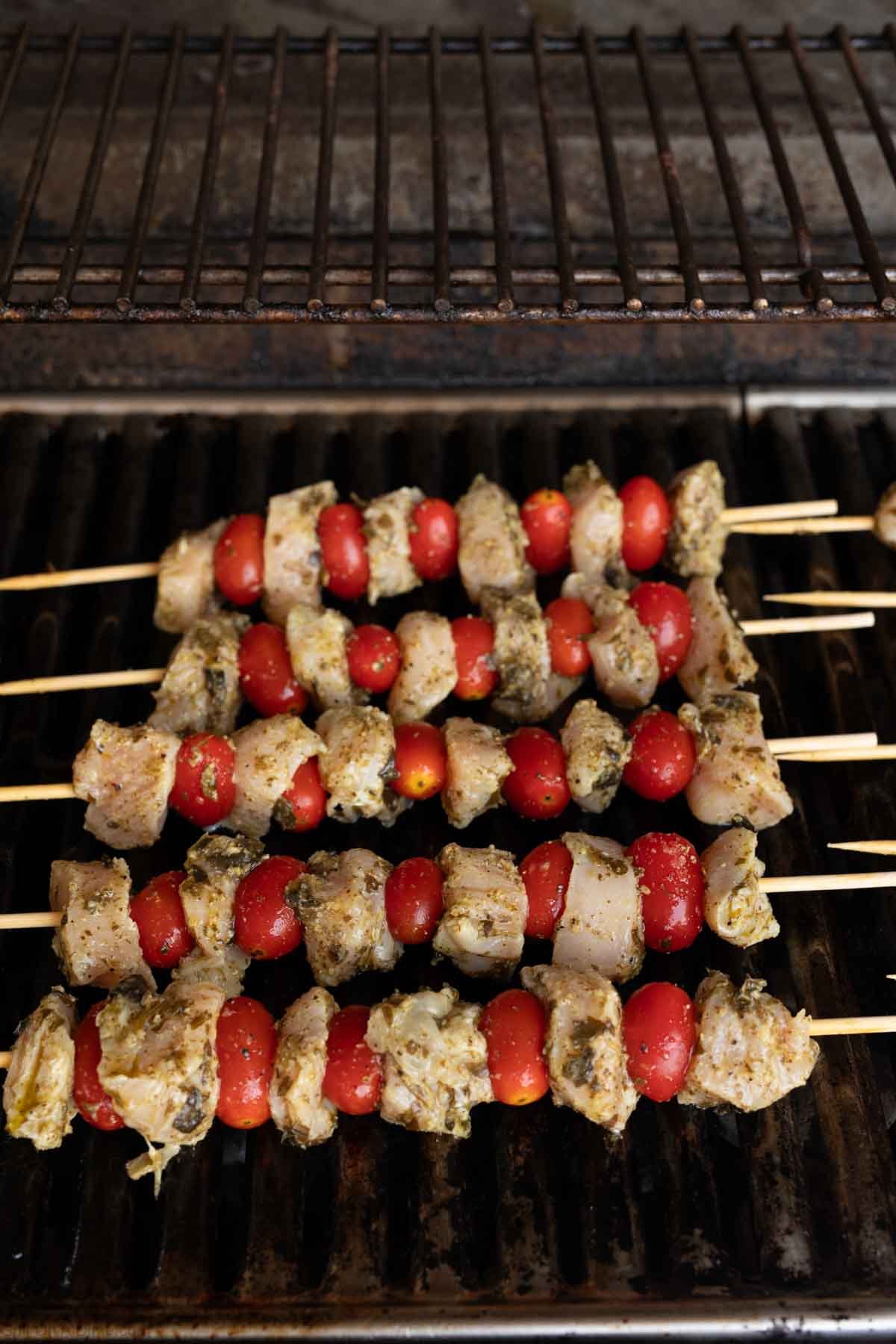 Chicken kabobs placed on grill grates 